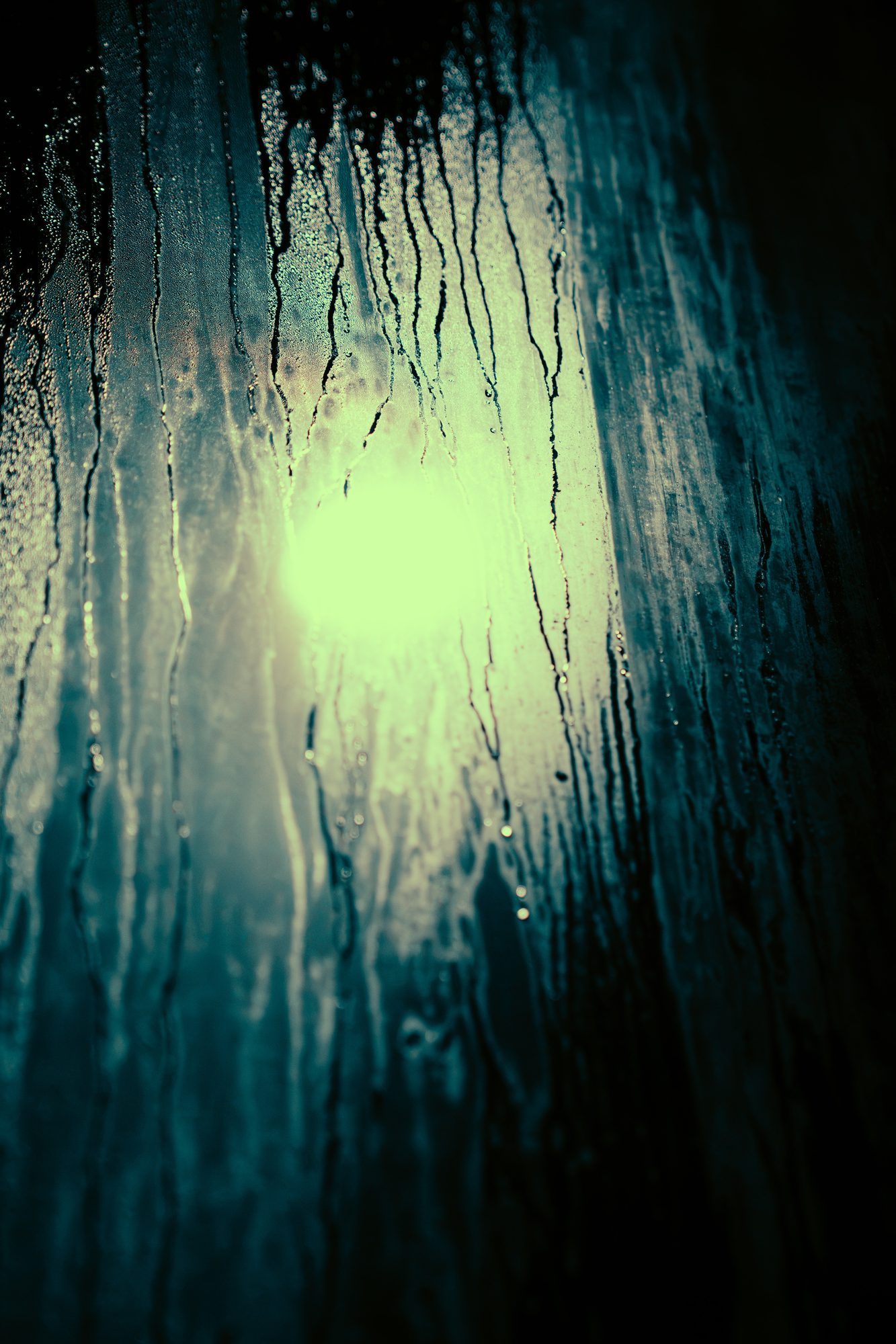 Water running down glass with a green light blooming through it